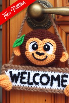 a crocheted monkey hanging from a door handle with the word welcome written on it