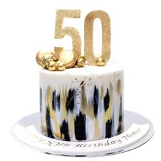 a 50th birthday cake decorated with gold and black icing on a white platter