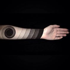 a person's arm is covered in black and white stripes with a circular tattoo on it