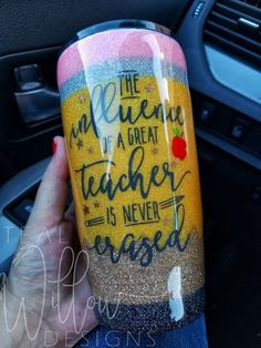 a person holding up a cup with writing on it in the middle of a car