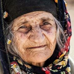 an old woman wearing a headscarf with flowers on it's head and eyes