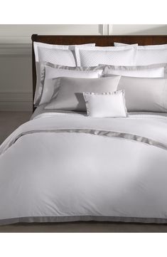 a bed with white sheets and pillows in a room