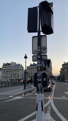 a traffic light sitting on the side of a road next to a street with buildings in the background