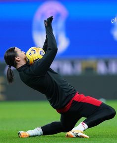 a female soccer player stretching to catch the ball in mid air with her arms stretched out