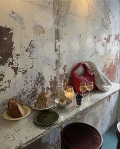 a table topped with plates of food next to a wall covered in chipped paint