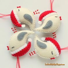 four felt ornaments in the shape of birds with red and white trims on them