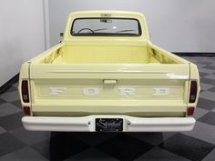 the back end of a yellow ford truck on a black and white checkered floor