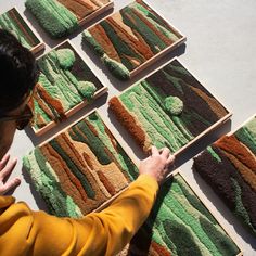 a person standing in front of several rugs on the floor and touching them with their hands