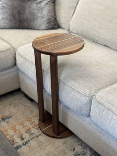 a small wooden table sitting on top of a white couch next to a gray couch