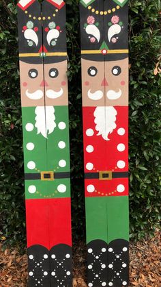 two wooden nutcrackers are standing next to each other in front of some bushes