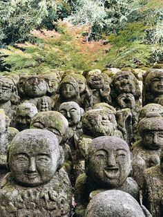 many heads are placed together in the shape of buddhas, with trees and bushes behind them