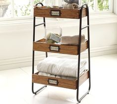 three tiered storage rack with towels and other items in front of a large window