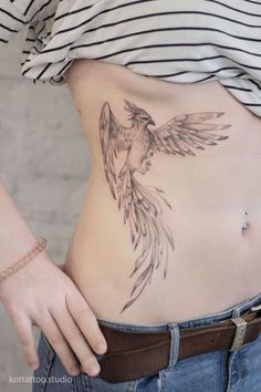 a woman's stomach with a bird tattoo on her belly and the bottom part of her stomach