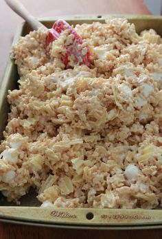 a pan filled with oatmeal and marshmallows next to a wooden table