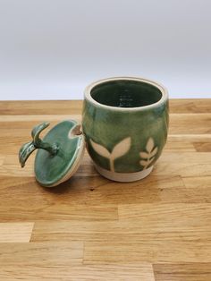 a green planter sitting on top of a wooden table next to a ceramic container