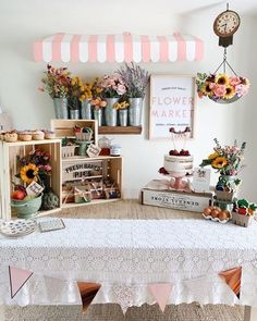 a white table topped with lots of cakes and desserts next to a wall mounted clock