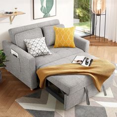 a living room with a gray couch, yellow and white throw pillows and pictures on the wall