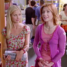 two young women standing next to each other in a room full of bookshelves