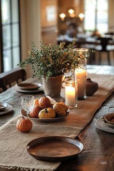 a wooden table topped with plates and candles