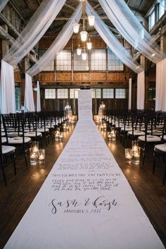 the aisle is decorated with candles and white draping for an elegant wedding ceremony