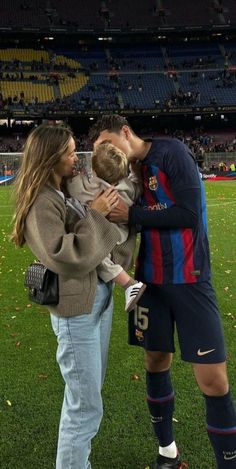 a man and woman holding a child in front of a soccer field