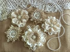 lace and crochet flowers are laid out on a piece of fabric with pearls