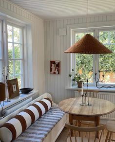 a living room filled with furniture next to two windows and a wooden table in front of a bay window