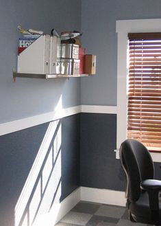 a desk and chair in a room with blue walls, checkered flooring and wooden shutters