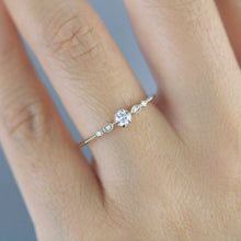 a woman's hand with a diamond ring on top of her finger, showing the side view