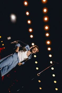 a man is performing on stage with lights in the background