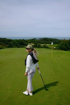 a woman standing on top of a green golf field