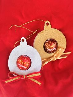 two christmas ornaments sitting on top of a red cloth