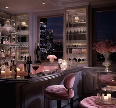 a bar with lots of bottles and glasses on the counter, along with two stools