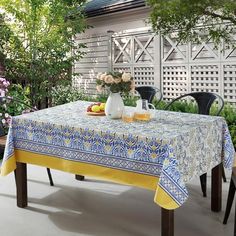 a table with flowers and fruit on it in front of a white fenced area