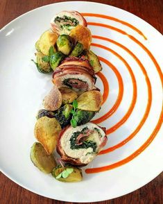 a white plate topped with rolls covered in veggies on top of a wooden table