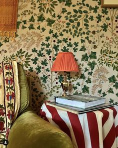 a green chair sitting next to a lamp on top of a table in front of a wall