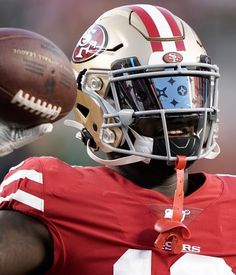 a close up of a football player wearing a helmet and holding a ball in his hand