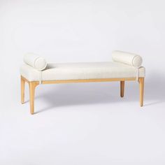 a white bench sitting on top of a white floor next to a wooden legrest