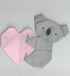 an origami koala with a pink piece of paper in the shape of a heart