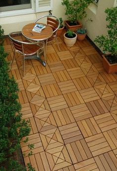 an outdoor patio with wooden flooring and potted plants