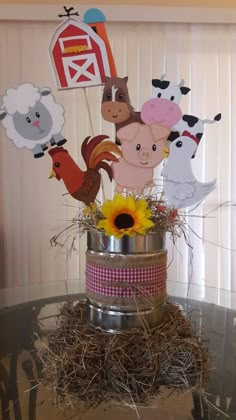 a cake decorated with farm animals on top of a tin can filled with hay and sunflowers