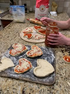 someone is making homemade pizzas on the kitchen counter with dough and sauce in front of them