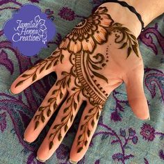 a hand with henna designs on it and purple flowers around the palm, which is decorated with green leaves