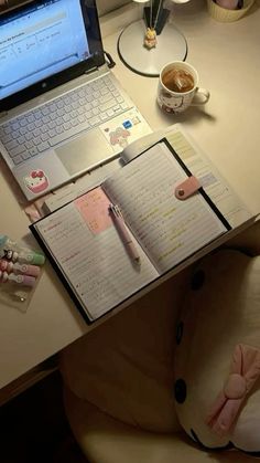 a laptop computer sitting on top of a desk next to a cup of coffee and pen