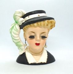 a ceramic figurine wearing a hat with a braid on it's head