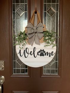 a welcome sign is hanging on the front door with a dog's paw and bow