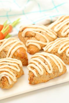 carrot scones with icing on a white plate next to some carrots and celery