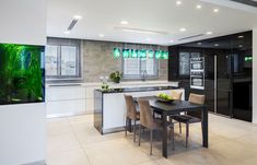 a modern kitchen with an aquarium in the center and dining room table next to it