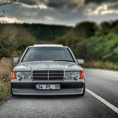 a mercedes benz parked on the side of the road with dark clouds in the background