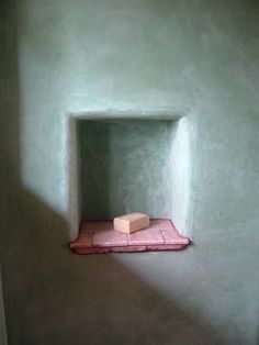 a small window in the corner of a green wall with a pink mat on it